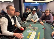 Ein professioneller Pokerspieler mit Sonnenbrille und Kappe sitzt an einem Pokertisch, umgeben von Chips und Karten.