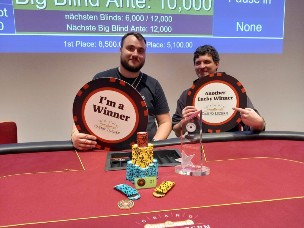 Ein Mann und eine Frau spielen auf einem grünen Pokertisch mit Chips und Karten. Der Mann hat eine Hand am Kinn und den Blick konzentriert auf seine Karten gerichtet, während die Frau mit nachdenklich
