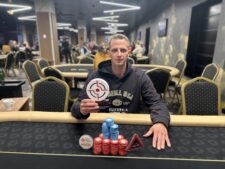 Ein Pokertisch mit Spielkarten, Jetons und einem Dealer-Button. Spieler sitzen um den Tisch herum und warten gespannt auf ihre Karten. Es herrscht eine konzentrierte Atmosphäre.