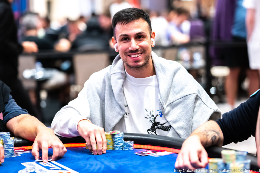 Ein Mann in einem schwarzen Anzug sitzt an einem Pokertisch und konzentriert sich auf seine Karten, während er an einem Turnier auf Zypern teilnimmt.