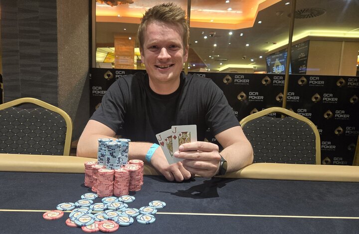 Ein Mann und eine Frau sitzen an einem Pokertisch und schauen sich konzentriert an, während im Hintergrund Chips und Karten zu sehen sind.