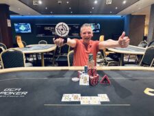 Ein Gruppenbild von Menschen, die an einem Pokertisch sitzen und Karten spielen. Es herrscht eine entspannte Atmosphäre in einem gut beleuchteten Raum.