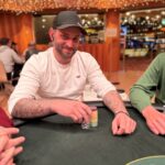 Ein Mann und eine Frau spielen eine Partie Poker an einem eleganten Spieltisch in einem luxuriösen Casino. Der Mann hat eine Hand mit Karten in der Hand, während die Frau konzentriert ihre Karten betrachtet