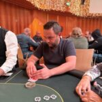 Ein Mann und eine Frau sitzen an einem Pokertisch und spielen Texas Hold'em. Der Mann hat eine Pokerhand aus Ass und König auf der Hand, während die Frau eine Hand aus zwei Pik-Karten hält. Der Pokert