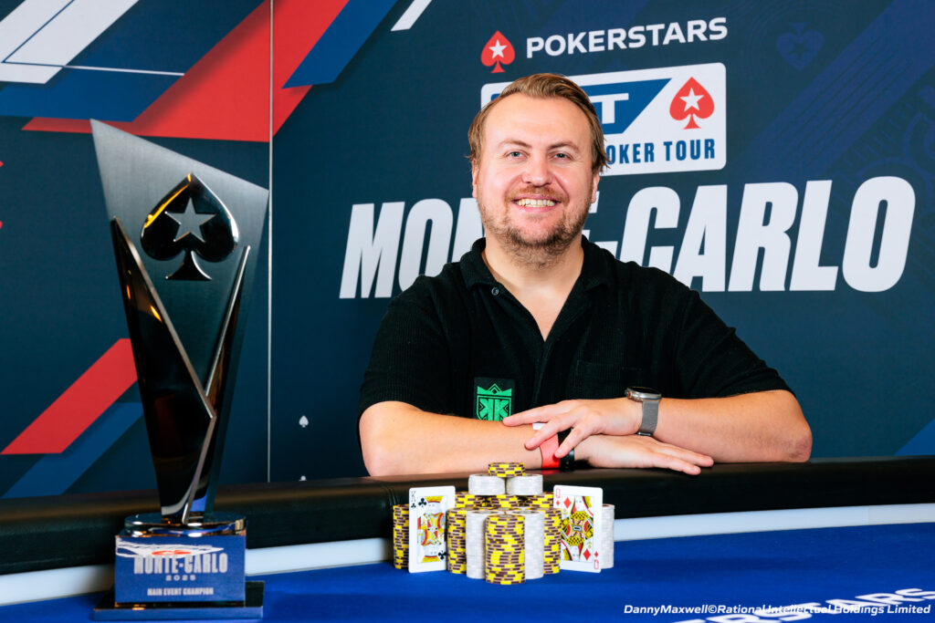 Ein Mann sitzt an einem Pokertisch in einem Casino, umgeben von anderen Spielern. Er hat eine Pokerhand aufgedeckt und schaut konzentriert auf die Karten. Die Atmosphäre ist gespannt und