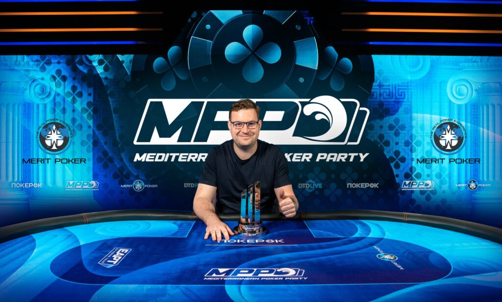 Ein Mann sitzt an einem Pokertisch und betrachtet konzentriert seine Karten.