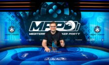 Ein Mann sitzt an einem Pokertisch und betrachtet konzentriert seine Karten.