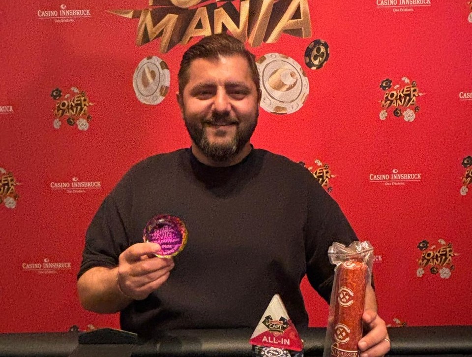 Ein Mann in schicker Kleidung und Sonnenbrille sitzt lässig an einem Pokertisch und hält Pokerchips in der Hand. Im Hintergrund sind andere Spieler und Spielkarten zu sehen.