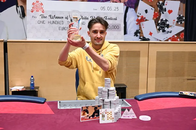 Ein glücklicher Pokerspieler mit einem breiten Lächeln hält seine Gewinnkarten in der Hand, während er vor einem leuchtenden Pokertisch sitzt.