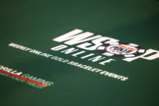 Ein professioneller Pokerspieler mit Sonnenbrille und Kappe sitzt an einem Tisch während des World Series of Poker-Turniers. Er hält Karten in der Hand und betrachtet konzentriert seine Gegner