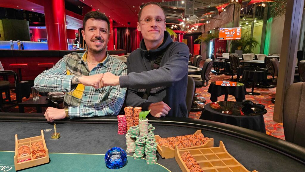 Ein Mann sitzt an einem Pokertisch und hält zwei Spielkarten in der Hand. Er schaut konzentriert auf den Tisch, umgeben von Pokerchips und einer Glücksspielszene im Hinter