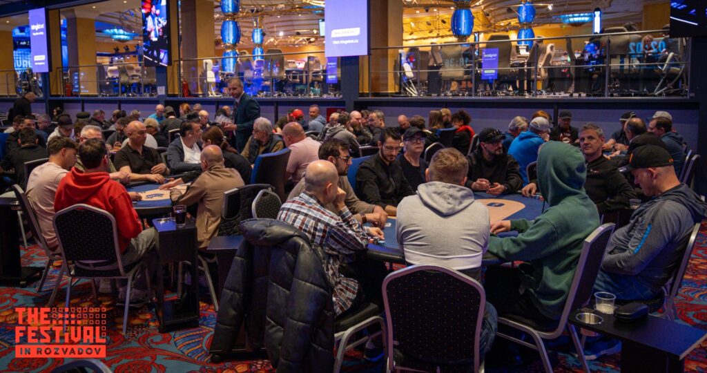 Ein Mann und eine Frau sitzen an einem Pokertisch und spielen Texas Hold'em. Der Mann hat eine Hand mit einem Ass und einer Zehn, während die Frau eine Hand mit einem Buben und einer Sieben hält. Sie sch