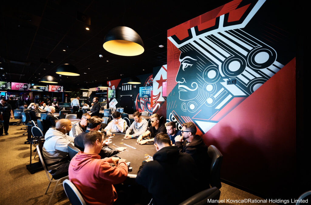 Ein stilllebendes Arrangement von Pokerspielkarten, die in einem Fächer angeordnet sind und auf einem Holztisch liegen.
