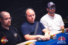 Ein Mann sitzt an einem Pokertisch und hält eine große Anzahl von Pokerchips in der Hand. Er scheint selbstbewusst und entschlossen zu sein.
