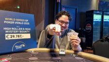 Ein Mann sitzt an einem Pokertisch und hält drei Spielkarten in der Hand. Er wirkt konzentriert und schaut intensiv auf seine Karten. Im Hintergrund sind weitere Spieler und Pokerchips zu sehen