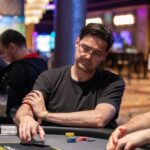 Ein Mann und eine Frau spielen Poker an einem eleganten Tisch in einem luxuriösen Casino. Die Frau hat gerade ihre Karten aufgedeckt und zeigt ein freudiges Lächeln, während der Mann konzentriert seine
