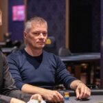 Ein entspannter Mann sitzt auf einem bequemen Sofa und spielt Poker mit einer Gruppe von Freunden. Die Karten liegen auf dem Tisch, während sie konzentriert ihre Hände betrachten. Gemüt