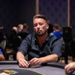 Ein Mann und eine Frau spielen Poker an einem eleganten Tisch in einem luxuriösen Casino. Sie halten Karten in der Hand und betrachten konzentriert ihre Chips. Die Atmosphäre ist spannungsgeladen und glamour