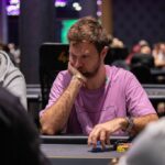 Ein Mann und eine Frau spielen Poker in einem eleganten Casino. Der Mann hält Karten in der Hand, während die Frau konzentriert auf ihre Karten schaut. Die Szene ist von einer luxuriösen Umgebung mit