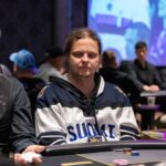 Ein professioneller Pokertisch mit grünem Filz, umgeben von Stühlen, Pokerchips und Spielkarten. Zwei Spieler sitzen gegenüber und halten ihre Karten. Die Spannung ist spürbar.