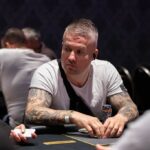Ein Mann und eine Frau sitzen an einem Pokertisch und spielen Texas Hold'em. Der Mann hat eine Hand mit Karten, während die Frau nachdenklich ihre Chips betrachtet. Im Hintergrund sind Pokerchips und Spiel