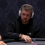 Ein Mann und eine Frau sitzen an einem Pokertisch und spielen Texas Hold'em. Der Mann hält Karten in der Hand und schaut konzentriert auf den Tisch, während die Frau ihre Karten betrachtet. Im