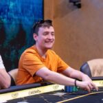 Ein Mann und eine Frau sitzen an einem Pokertisch und spielen Texas Hold'em. Der Mann hat einen Stapel Chips vor sich und hält Karten in der Hand, während die Frau konzentriert auf ihre Karten schaut.