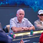 Ein Stapel von Pokerchips in verschiedenen Farben und Werten auf einem grünen Pokertisch.