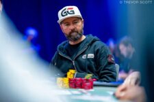 Ein Mann in einem dunklen Anzug sitzt an einem Pokertisch bei der World Series of Poker 2025 und betrachtet konzentriert seine Karten. Um ihn herum sind weitere Spieler und Zuschauer zu sehen.