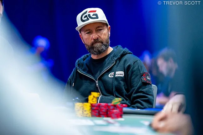 Ein Mann in einem dunklen Anzug sitzt an einem Pokertisch bei der World Series of Poker 2025 und betrachtet konzentriert seine Karten. Um ihn herum sind weitere Spieler und Zuschauer zu sehen.
