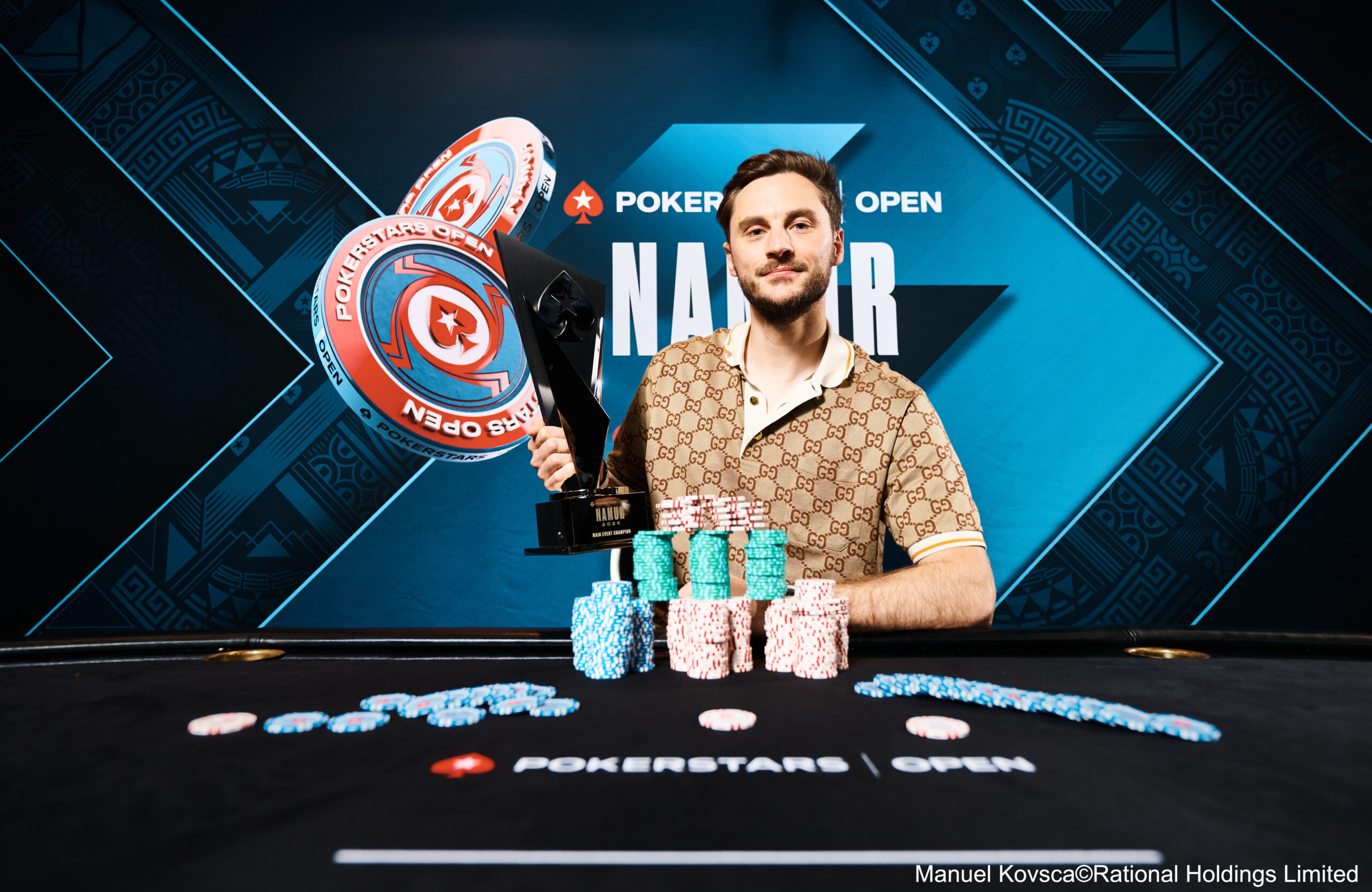 Ein Mann spielt Poker an einem Tisch in einem eleganten Casino. Er hat eine ernste Miene und hält Karten in der Hand, während er von anderen Spielern umgeben ist. Der Raum ist stilvoll mit gedä