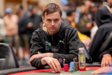 Ein Mann sitzt an einem Pokertisch bei der World Series of Poker (WSOP) 2025. Er trägt eine schwarze Kappe und konzentriert sich auf seine Karten. Im Hintergrund sind weitere Spieler und