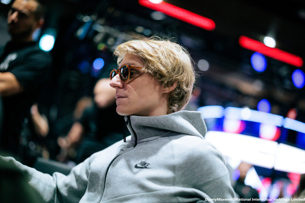 Ein junger Mann namens Lukas Hafner sitzt an einem Pokertisch und hält Karten in der Hand, während er konzentriert auf seine Gegner schaut.