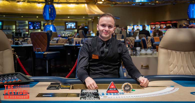 Ein Gruppenfoto von Pokerspielern, die am "The Festival Rozvadov Mixed Games Main Event" teilnehmen. Einige Spieler sitzen an einem Pokertisch, während andere um den Tisch herum stehen. Die Spieler
