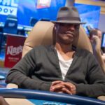 Ein Mann sitzt an einem Pokertisch während eines Mixed-Games-Main-Events. Er hat eine Brille auf und konzentriert sich auf seine Karten. Im Hintergrund sind weitere Spieler und Dealer zu sehen.