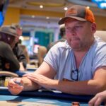 Ein Mann sitzt an einem Pokertisch während des "The Festival Rozvadov Mixed Games Main Event". Er hat eine Hand voll Spielkarten und konzentriert sich auf das Spiel.