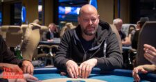 Ein Mann sitzt an einem Pokertisch mit grüner Filzdecke während eines Pokerturniers im King's Casino in Rozvadov. Er trägt eine Sonnenbrille und hat Pokerchips vor sich auf dem T