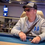 Ein Mann sitzt an einem Pokertisch während des "The Festival Rozvadov Mixed Games Main Event". Er konzentriert sich auf seine Karten und Chips.