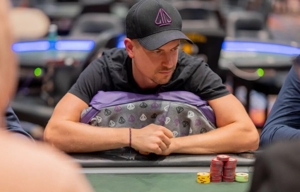 Ein Mann in einem dunklen Anzug sitzt an einem Pokertisch bei der WSOP 2025. Er hat blonde Haare und trägt eine Sonnenbrille.
