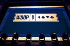 Ein Mann spielt Poker während des World Series of Poker (WSOP) Turniers, umgeben von anderen Spielern und Zuschauern in einem großen Veranstaltungsraum.