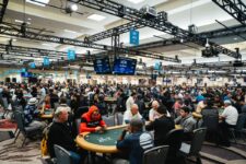 Ein voll besetzter Raum während der World Series of Poker, mit vielen Pokertischen und Spielern, die konzentriert Texas Hold'em spielen.